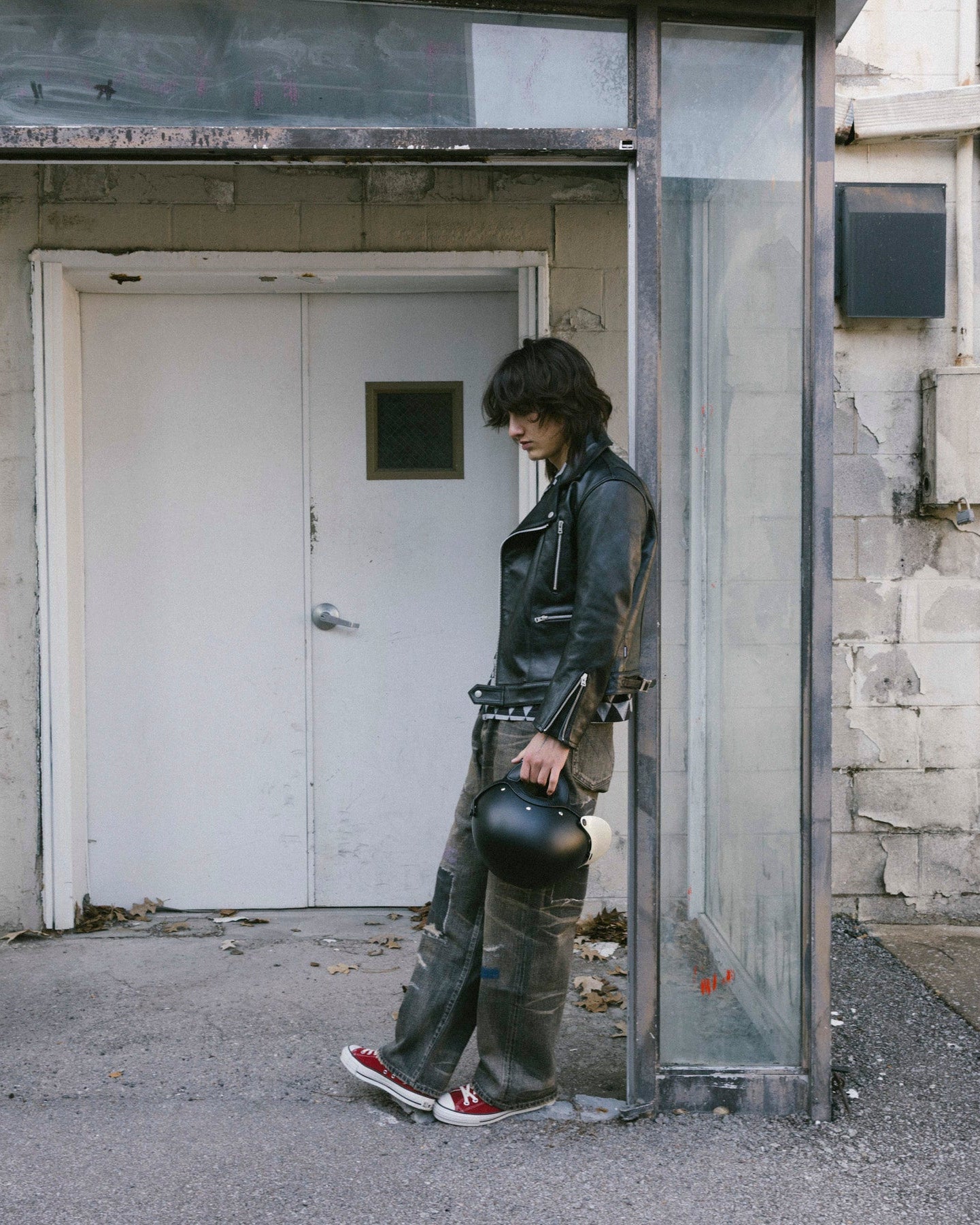 Person standing in front of a door with a helmet in an urban setting